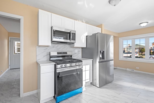 kitchen with white cabinets, appliances with stainless steel finishes, and tasteful backsplash