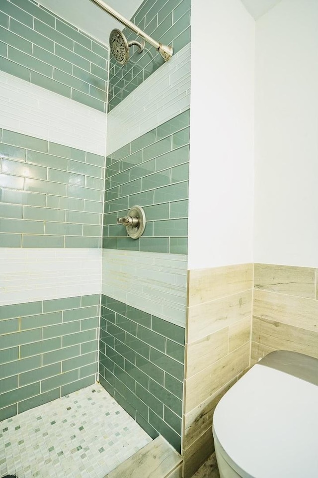 bathroom featuring a tile shower, tile walls, and toilet