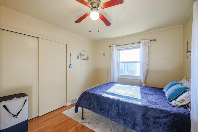 bedroom featuring ceiling fan, wood-type flooring, crown molding, and a closet