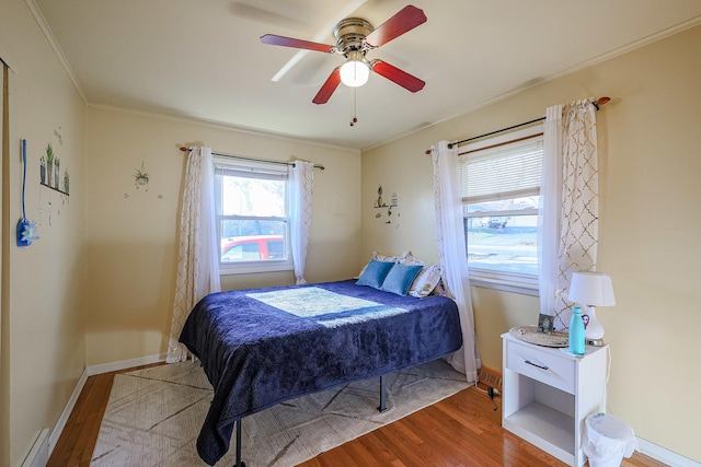 bedroom featuring ceiling fan, wood-type flooring, crown molding, and a baseboard heating unit