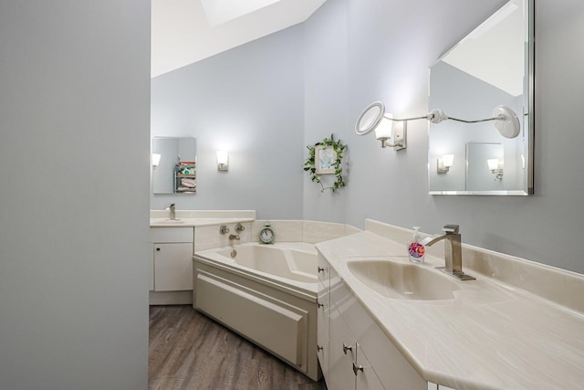 bathroom featuring hardwood / wood-style floors, a bathtub, lofted ceiling with skylight, and vanity