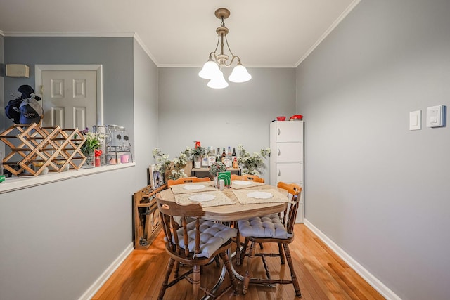 dining room with wood-type flooring, ornamental molding, and a chandelier