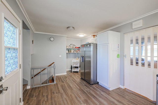 kitchen with white cabinets, stainless steel fridge, wood-type flooring, and crown molding