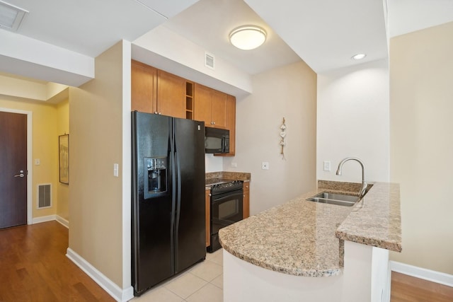 kitchen with kitchen peninsula, sink, light hardwood / wood-style floors, and black appliances