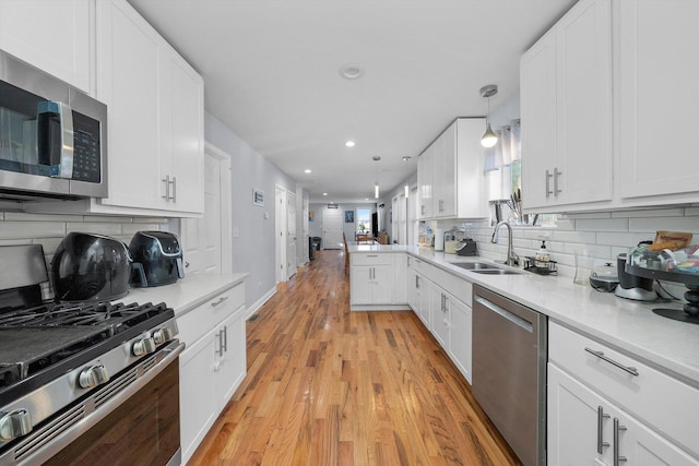 kitchen featuring white cabinets, decorative light fixtures, sink, and stainless steel appliances