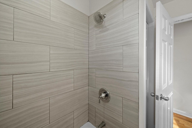 bathroom with a tile shower and hardwood / wood-style floors