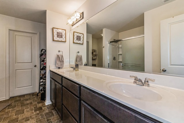 bathroom featuring a shower with door and vanity