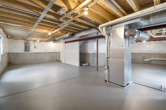 basement featuring electric panel and heating unit