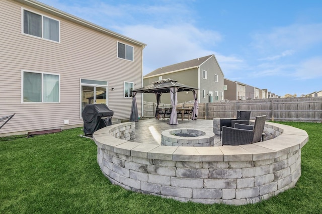 rear view of house with a gazebo, a patio area, an outdoor fire pit, and a lawn