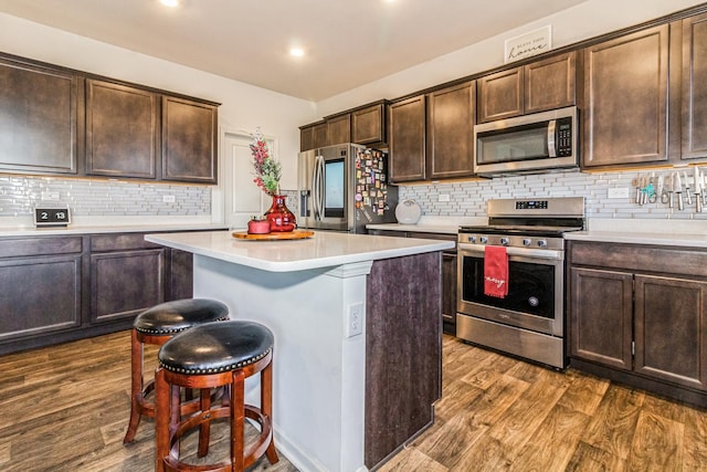 kitchen with dark brown cabinets, a kitchen island, dark hardwood / wood-style flooring, and appliances with stainless steel finishes