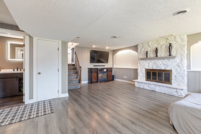 unfurnished living room featuring sink, a textured ceiling, a fireplace, and wood-type flooring