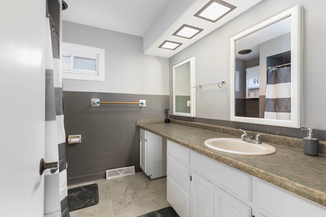 bathroom with vanity and tile walls