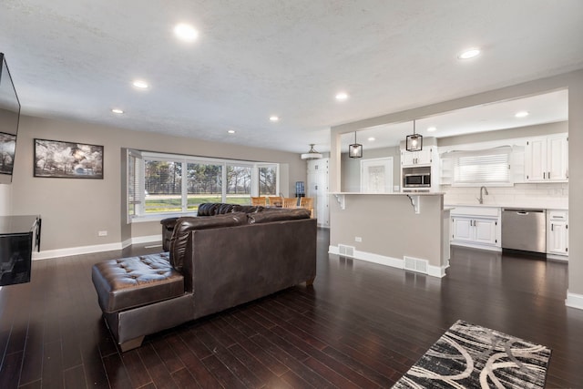 living room featuring dark hardwood / wood-style flooring, sink, and a wealth of natural light