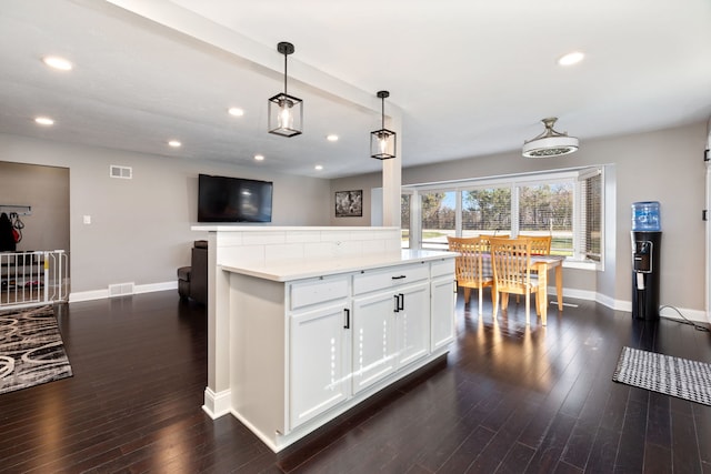 kitchen with a kitchen island, dark wood-type flooring, pendant lighting, and white cabinets