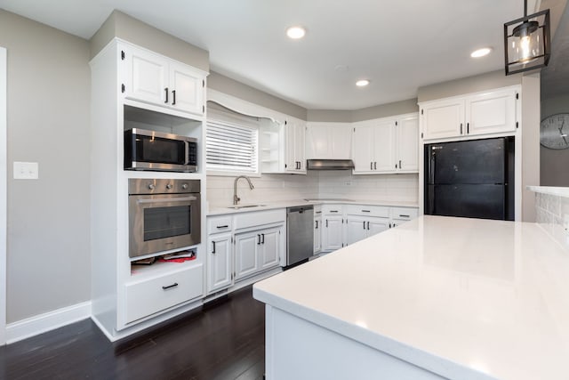 kitchen with sink, appliances with stainless steel finishes, white cabinetry, decorative backsplash, and decorative light fixtures