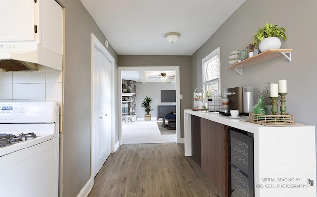 kitchen with backsplash, premium range hood, wine cooler, light hardwood / wood-style floors, and white range with gas cooktop