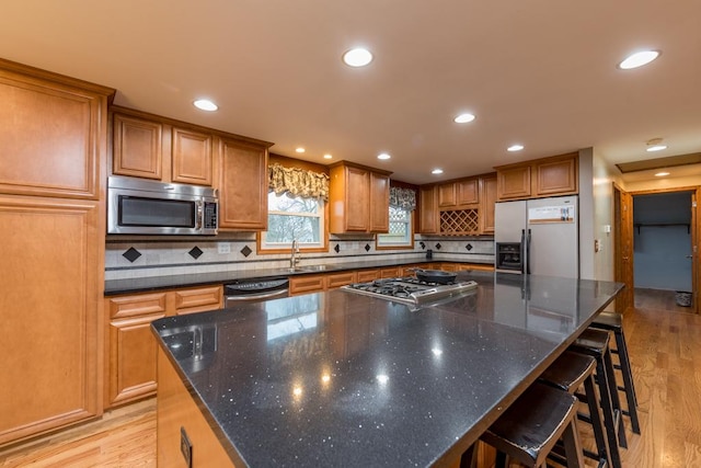 kitchen with sink, a kitchen island, stainless steel appliances, and light hardwood / wood-style floors