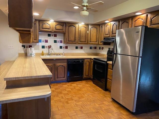 kitchen featuring ceiling fan, sink, range hood, backsplash, and black appliances