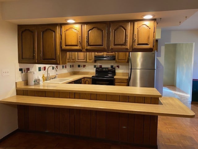 kitchen featuring kitchen peninsula, dark parquet floors, sink, black range with electric stovetop, and stainless steel refrigerator