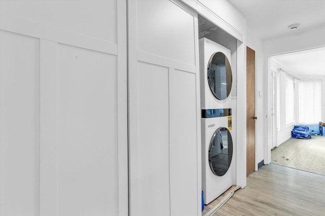 washroom with stacked washing maching and dryer and light wood-type flooring