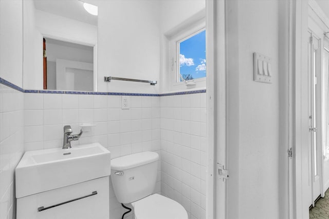 bathroom with vanity, toilet, and tile walls