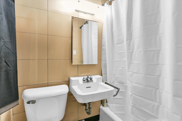 bathroom featuring toilet, sink, and tile walls