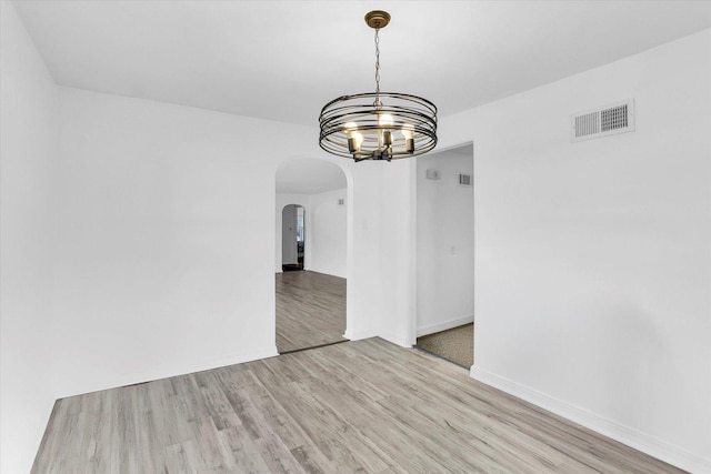 unfurnished dining area with light wood-type flooring and an inviting chandelier