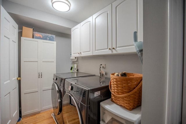 laundry room with cabinets, light wood-type flooring, and washing machine and clothes dryer