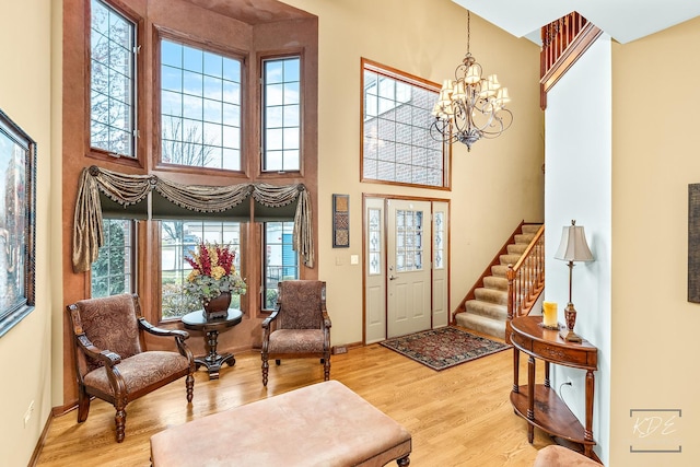 foyer entrance with hardwood / wood-style floors, a high ceiling, and a notable chandelier