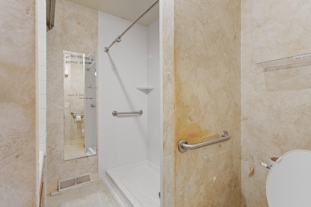 bathroom with tile patterned flooring and a tile shower