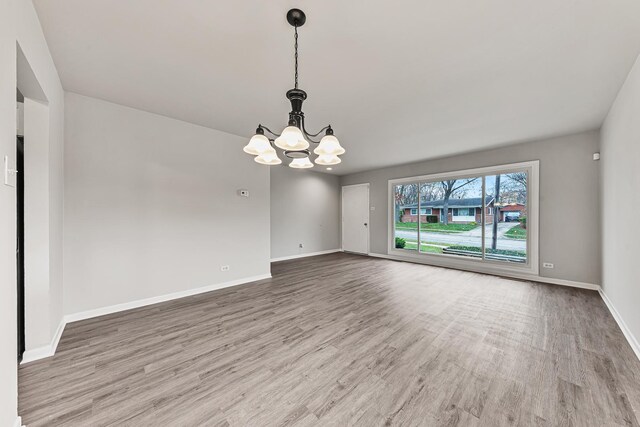 empty room with light hardwood / wood-style floors and an inviting chandelier