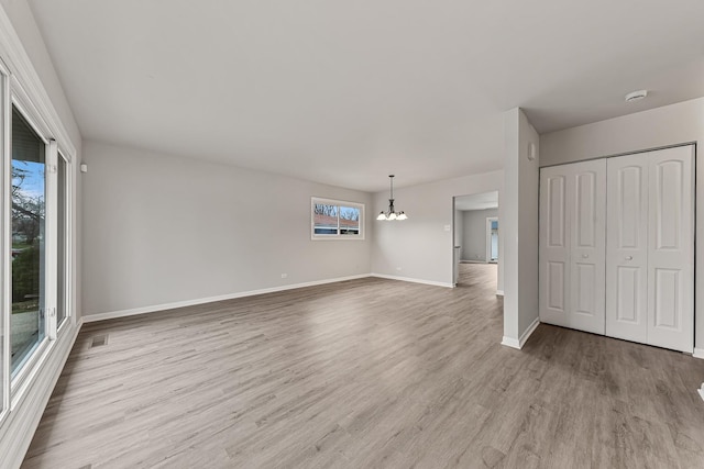 unfurnished living room with light hardwood / wood-style floors and an inviting chandelier