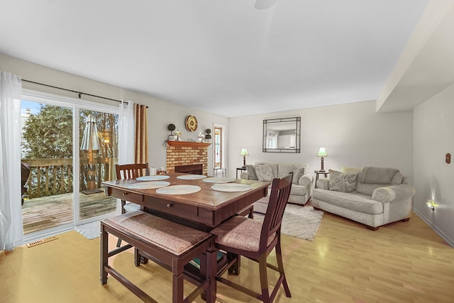 dining area with light hardwood / wood-style floors and a fireplace