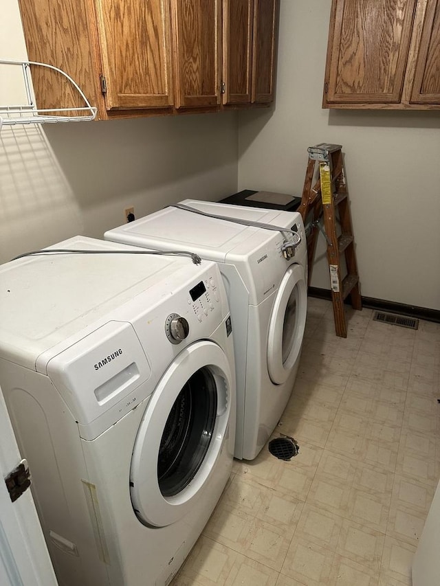 clothes washing area with cabinets and washing machine and clothes dryer