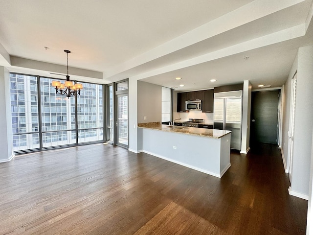 kitchen with light stone countertops, kitchen peninsula, a wealth of natural light, and stainless steel appliances