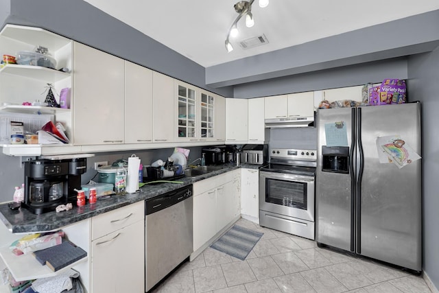 kitchen featuring sink, stainless steel appliances, white cabinets, dark stone counters, and light tile patterned flooring