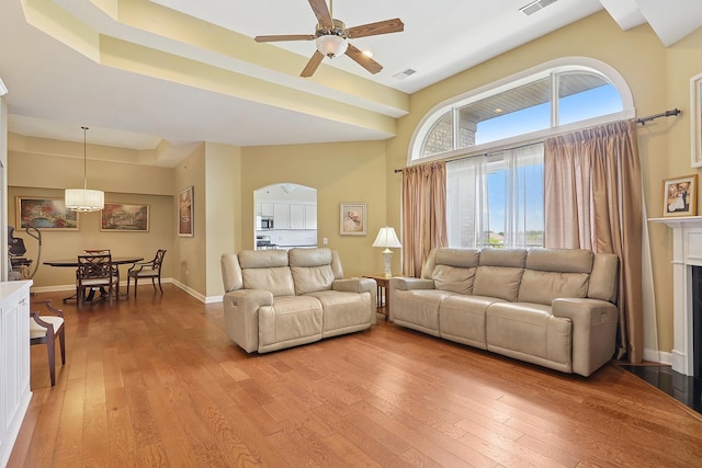 11110 Waters Edge Dr Unit 4D, Orland Park, IL 60467 - living room featuring arched walkways, light wood-style floors, a ceiling fan, baseboards, and a towering ceiling