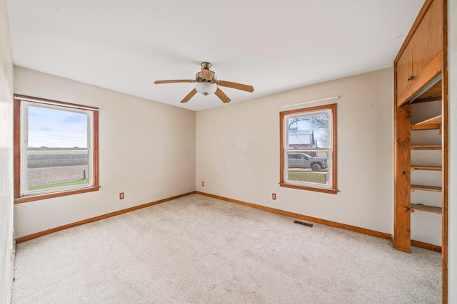 unfurnished room featuring a wealth of natural light, ceiling fan, and light carpet