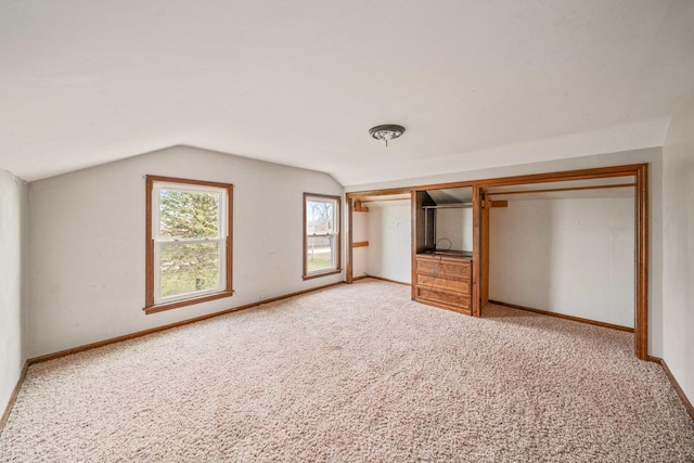 unfurnished bedroom featuring a closet, light carpet, and vaulted ceiling