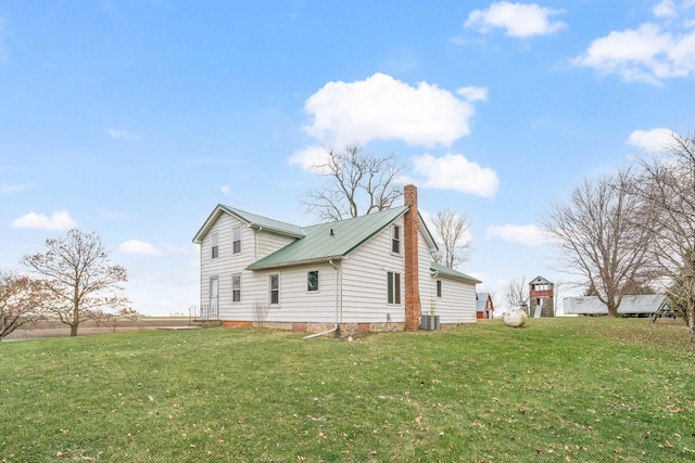 view of side of property featuring a lawn and central AC