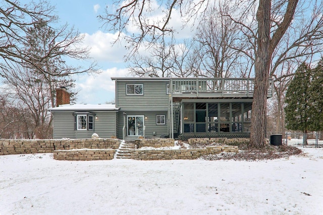 snow covered property featuring cooling unit and a sunroom