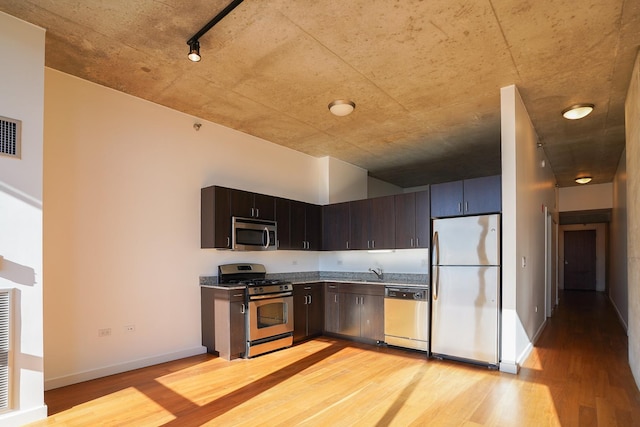 kitchen featuring appliances with stainless steel finishes, light wood-type flooring, dark brown cabinets, and sink