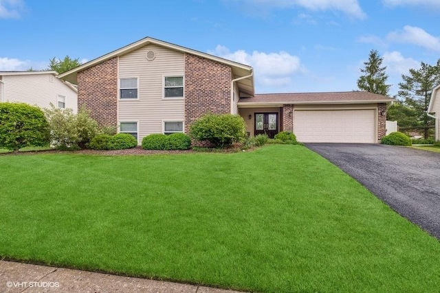 split level home with brick siding, a front lawn, an attached garage, and aphalt driveway