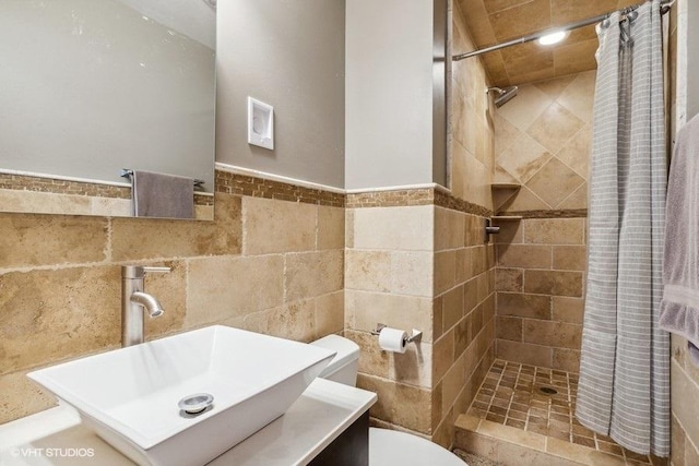 full bath featuring vanity, a stall shower, toilet, wainscoting, and tile walls