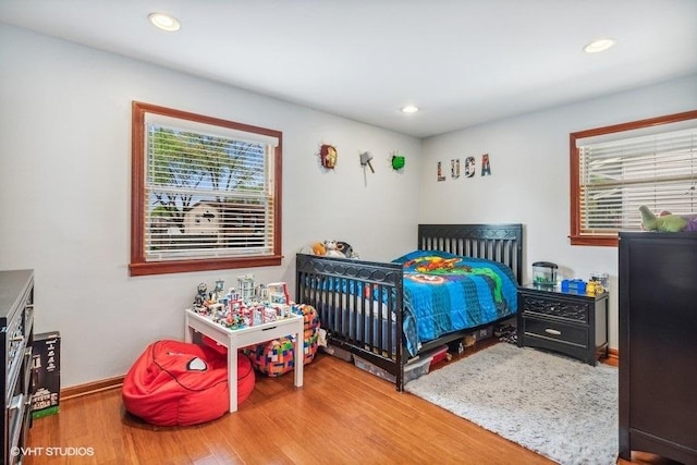 bedroom featuring wood finished floors, baseboards, and recessed lighting
