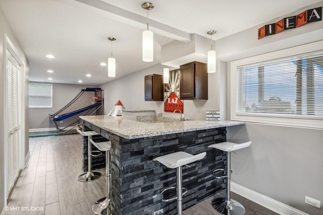 kitchen with dark brown cabinets, baseboards, wood finished floors, and a kitchen bar