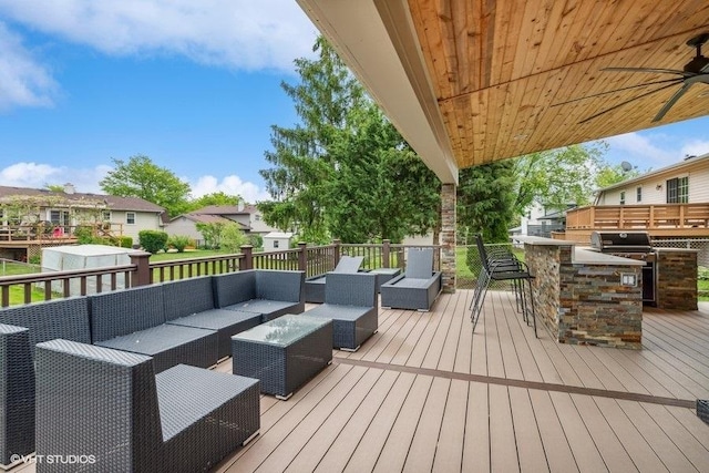 deck with outdoor dry bar, an outdoor kitchen, an outdoor living space, a grill, and a ceiling fan