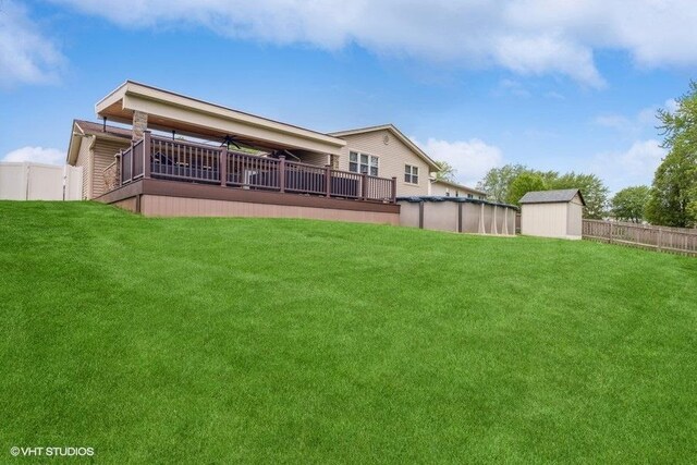 rear view of property with a storage shed, fence, a covered pool, and a lawn