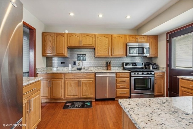 kitchen with stainless steel appliances, dark wood finished floors, a sink, and decorative backsplash