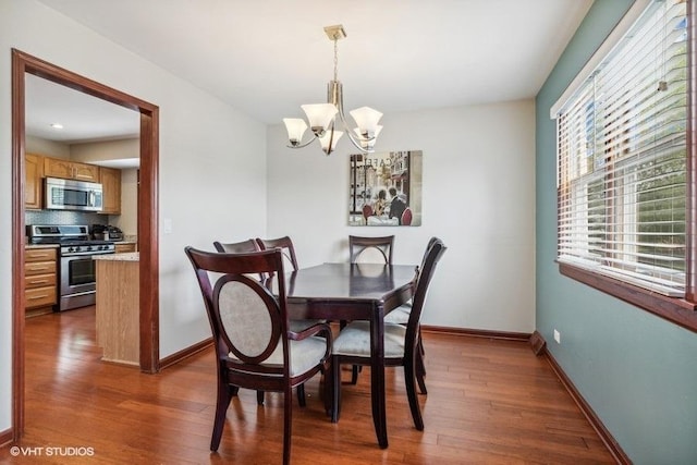 dining space featuring a chandelier, wood finished floors, and baseboards